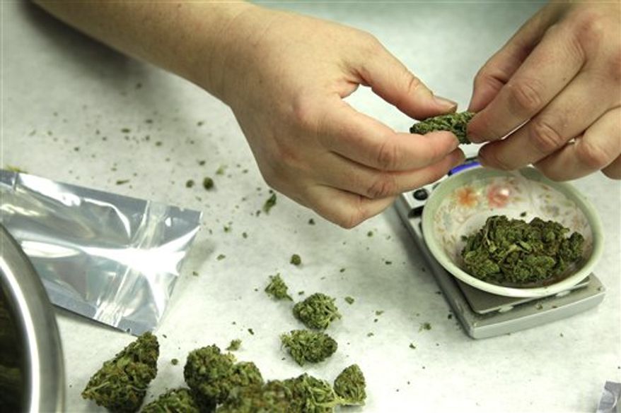 ** FILE ** In this Oct. 10, 2012, photo, marijuana is weighed and packaged for sale at the Northwest Patient Resource Center medical marijuana dispensary in Seattle. (Associated Press)