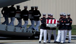 **FILE** Carry teams move flag-draped transfer cases of the remains of the four Americans killed in Benghazi, Libya, from a transport plane during the Transfer of Remains ceremony on Sept. 14, 2012, at Andrews Air Force Base in suburban Washington. (Associated Press)