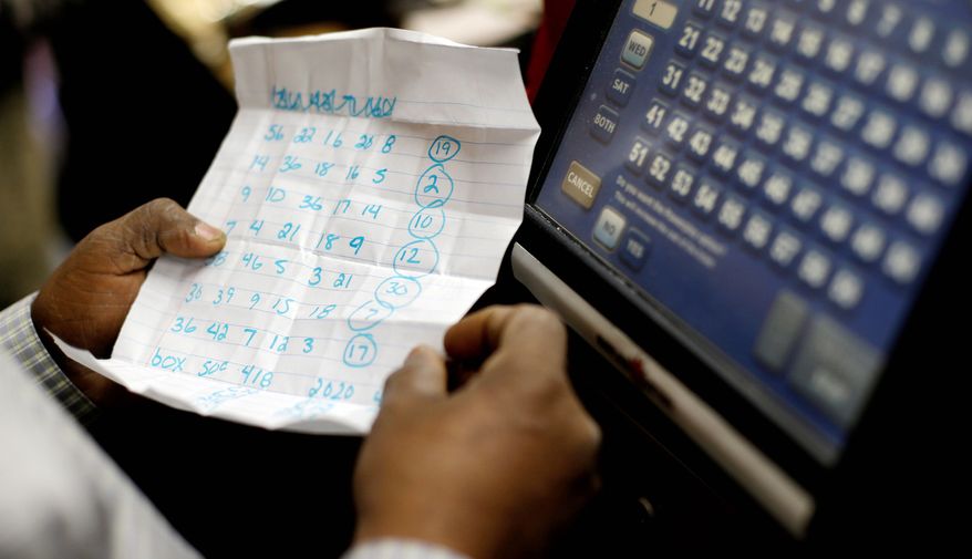 Baltimore convenience store clerk Woody Amlak inserts the chosen Powerball numbers — a combination of relatives’ birthdays and addresses — for first-time Powerball player Javon Lee. The jackpot was expected to exceed $550 million before the 11 p.m. drawing. (Associated Press)
