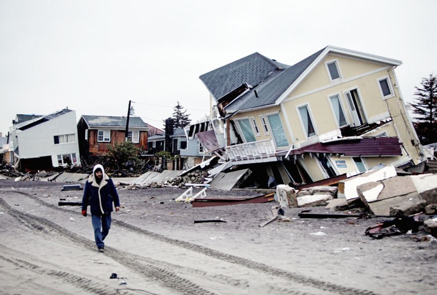 A man walks past destroyed homes on the Rockaway Peninsula in the New York borough of Queens on Tuesday, Nov. 27, 2012. (AP Photo/Seth Wenig)