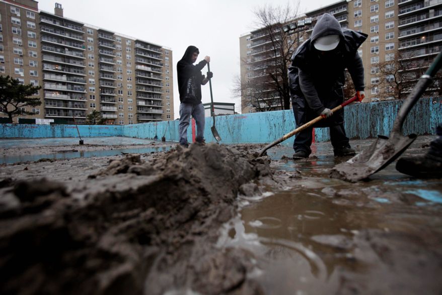 Men shovel out a pool filled with mud on the Rockaway Peninsula in the New York borough of Queens on Tuesday, Nov. 27, 2012. (AP Photo/Seth Wenig)