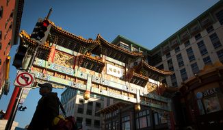 A man is silhouetted against the sunlit Chinatown arch in Chinatown near Seventh and H streets Northwest in Washington on Wednesday, Nov. 28, 2012. (The Washington Times)