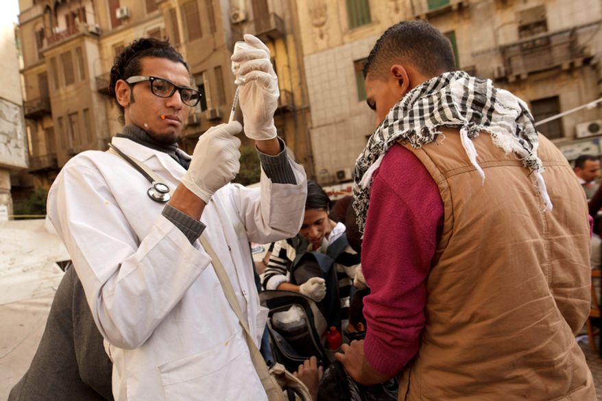 A volunteer doctor at a field hospital in Tahrir Square in Cairo prepares an injection for a protester wounded during clashes with security forces on Thursday, Nov. 29, 2012. (AP Photo/Maya Alleruzzo)