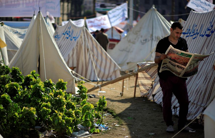 An Egyptian protester reads the Wafd, a local newspaper, next to tents occupied by protesters in Tahrir Square in Cairo on Wednesday, Nov. 28, 2012. Egyptian state television says the country's highest appeal court has decided to suspend its work nationwide to protest the president's decrees giving himself nearly absolute powers. (AP Photo/Khalil Hamra)