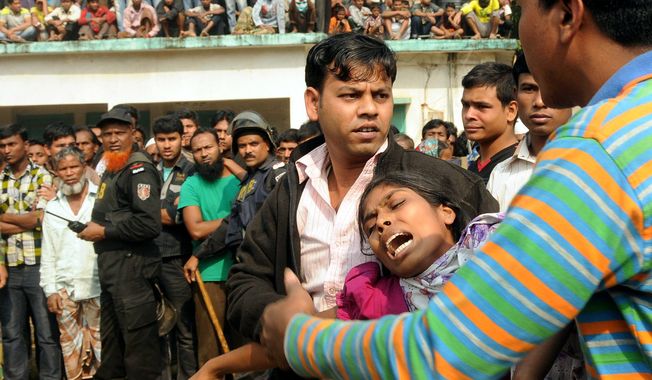 ** FILE ** People console a woman whose relative was killed in a fire at a garment factory outside Dhaka, Bangladesh, Sunday, Nov. 25, 2012. At least 112 people were killed late Saturday night in a fire that raced through the multi-story garment factory just outside of Bangladesh&#x27;s capital, an official said Sunday. (AP Photo/Hasan Raza)