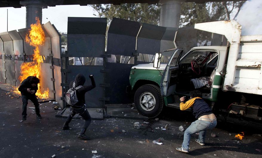Protestors throw stones over the steel security barriers around the National Congress, where the swearing in of new Mexican President Enrique Pena Nieto is taking place in Mexico City, Saturday, Dec. 1, 2012. (AP Photo/Eduardo Verdugo)