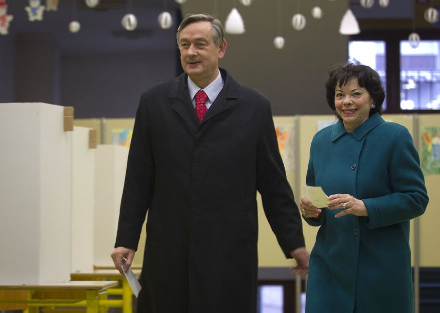 Incumbent Slovenian President Danilo Turk, accompanied by his wife, Barbara Miklic, prepares to cast his ballot at a polling station in Ljubljana, Slovenia, on Sunday, Dec. 2, 2012. Small, crisis-hit Slovenia is choosing a president in an atmosphere of uncertainty and growing discontent with cost-cutting measures designed to avoid an international bailout. (AP Photo/Darko Bandic)