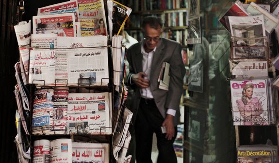 An Egyptian walks past a stand displaying state-owned newspapers in Cairo on Dec. 4, 2012. Most independent Egyptian newspapers suspended publication of that day&#39;s edition in protest over the hurried drafting of the country&#39;s new constitution adopted by an Islamist-led panel. (Associated Press)