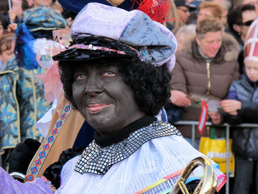 A person dressed as Zwarte Piet, or Black Pete, attends a parade after Sinterklaas, as the Dutch call Santa Claus, arrived by boat in Amsterdam on Sunday, Nov. 18, 2012. (AP Photo/Margriet Faber)