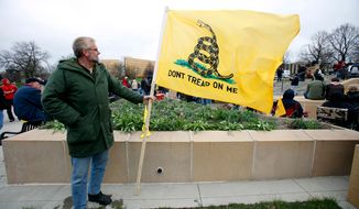 A tea party supporter holds a Don&#39;t Tread on Me flag during a rally on Saturday, April 16, 2011, at the Statehouse in Des Moines, Iowa. (AP Photo/Charlie Neibergall)