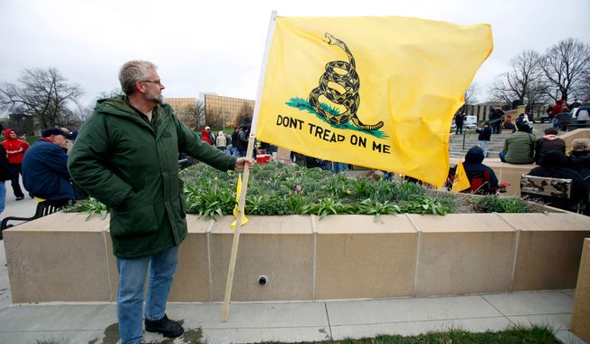 A tea party supporter holds a Don&#x27;t Tread on Me flag during a rally on Saturday, April 16, 2011, at the Statehouse in Des Moines, Iowa. (AP Photo/Charlie Neibergall)