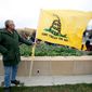 A tea party supporter holds a Don&#39;t Tread on Me flag during a rally on Saturday, April 16, 2011, at the Statehouse in Des Moines, Iowa. (AP Photo/Charlie Neibergall)