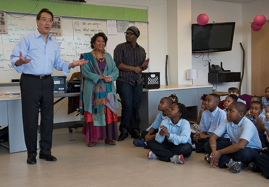 World renowned cellist Yo Yo Ma, left, greets students at Savoy Elementary School in Southeast Washington, D.C. before conducting a special workshop with former New York City Ballet principal dancer Damiam Woetzel on Tuesday, Dec. 4, 2012. The students and the artists then performed for the entire school. The artists were brought to the school as part of the Innovative Schedule for the Arts, a new program started up at the school only a couple of months ago that integrates the arts into students' everyday schedules. (Barbara L. Salisbury/The Washington Times)