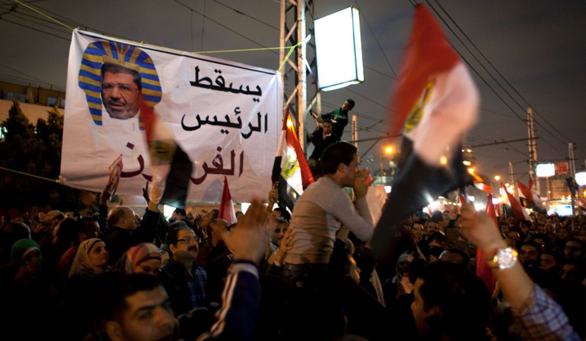 Egyptian protesters carry national flags and chant slogans against the Muslim Brotherhood during a rally Dec. 4, 2012, in front of the presidential palace in Cairo. Tensions grew over Islamist President Mohammed Morsi&#x27;s seizure of nearly unrestricted powers and a draft constitution hurriedly adopted by his allies. Arabic on the banner reads, &quot;down with the pharaoh president.&quot; (Associated Press)