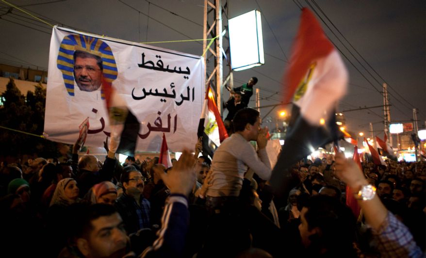 Egyptian protesters carry national flags and chant slogans against the Muslim Brotherhood during a rally Dec. 4, 2012, in front of the presidential palace in Cairo. Tensions grew over Islamist President Mohammed Morsi's seizure of nearly unrestricted powers and a draft constitution hurriedly adopted by his allies. Arabic on the banner reads, "down with the pharaoh president." (Associated Press)