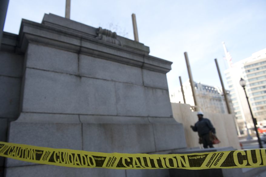 A construction worker stands inside the fenced off area outside the Wilson Building in Washington, D.C. on Thursday, Dec. 6, 2012. Work is underway to build a viewing platform here for the Inauguration parade. This Pennsylvania Avenue entrance is likely to be closed to the public through March so that the platform can be torn down after Jan. 21. (Barbara L. Salisbury/The Washington Times)