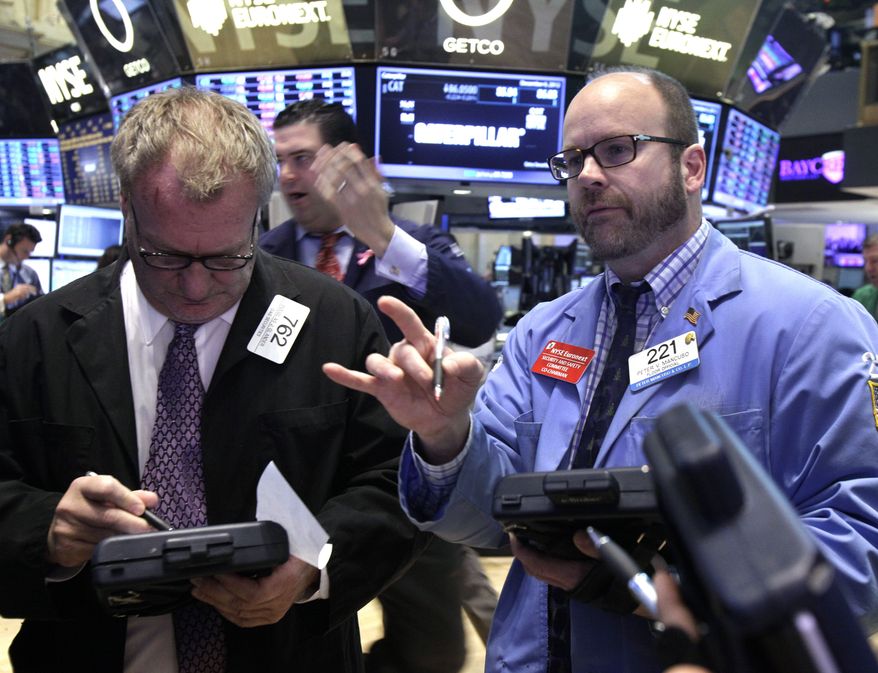 Traders Douglas Glander (left) and Peter Mancuso (right) work on the floor of the New York Stock Exchange on Thursday, Dec. 6, 2012. (AP Photo/Richard Drew)