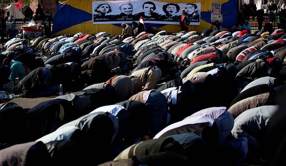 Egyptian protesters opposing president Mohammed Morsi attend Friday prayers beneath with a poster depicting protesters killed in the Egyptian revolution, at Tahrir Square, Cairo, Egypt, Friday, Dec. 7, 2012. Arabic on the poster reads their names from right &quot;Islam, Jaber, Khalid Said, Emad Effat and Mina Daniel.&quot; Thousands of Egyptians took to the streets after Friday midday prayers in rival rallies and marches across Cairo, as the standoff deepened over what opponents call the Islamist president&#39;s power grab, raising the specter of more violence. (AP Photo/Nasser Nasser)
