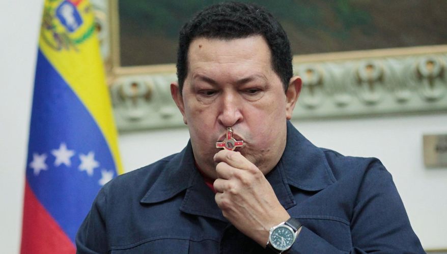 ** FILE ** Venezuelan President Hugo Chavez kisses a crucifix before a surgery in Cuba to treat cancer in December 2012. (Associated Press)