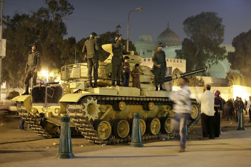 An Egyptian protester takes a picture with his mobile phone of his children on top of an Egyptian army tank outside the presidential palace (background) in Cairo on Saturday, Dec. 8, 2012. (AP Photo/Hassan Ammar)