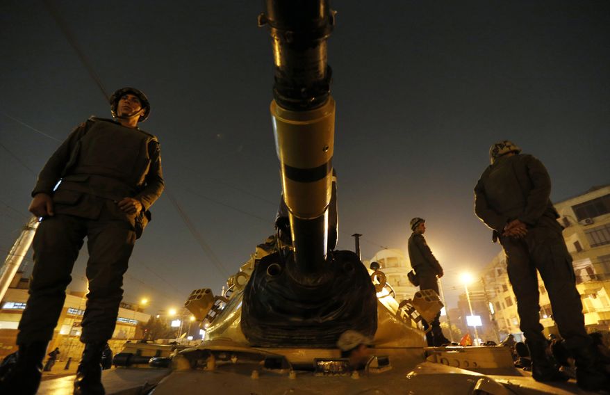 Egyptian soldiers stand guard atop a tank in front of the presidential palace in Cairo on Sunday, Dec. 9, 2012. (AP Photo/Petr David Josek)