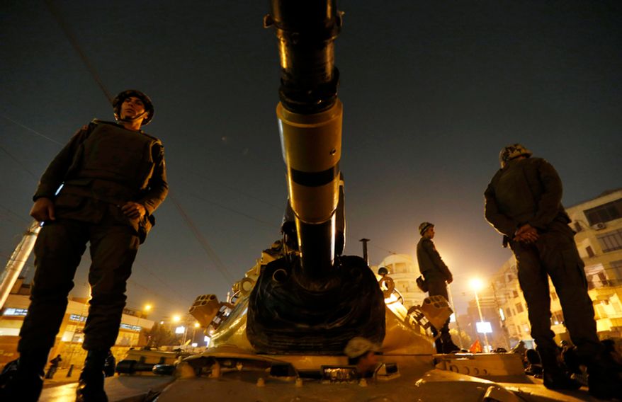 Soldiers stand guard atop a tank in front of the presidential palace in Cairo on Dec. 9, 2012. (Associated Press)