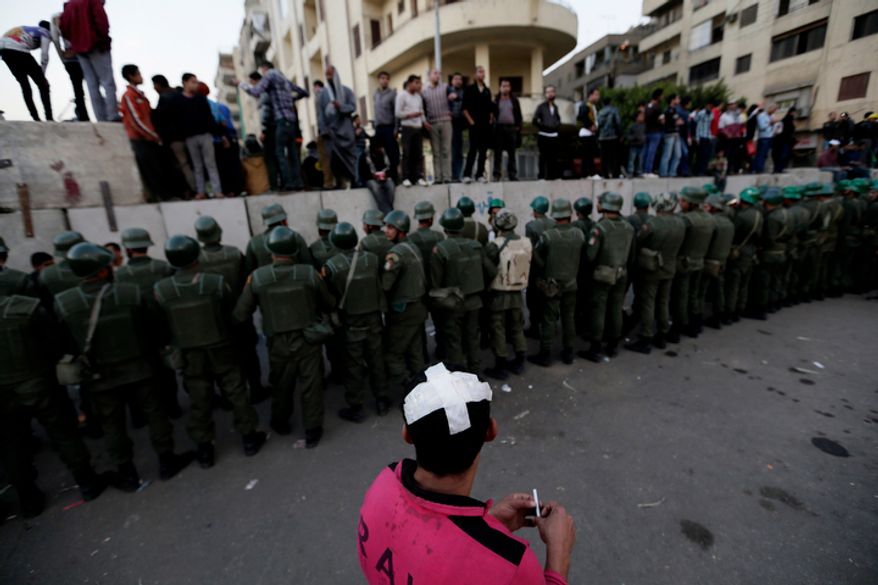 Egyptian army soldiers stand guard as protesters stand on top of cement blocks near the presidential palace in Cairo on Dec. 9, 2012. (Associated Press)