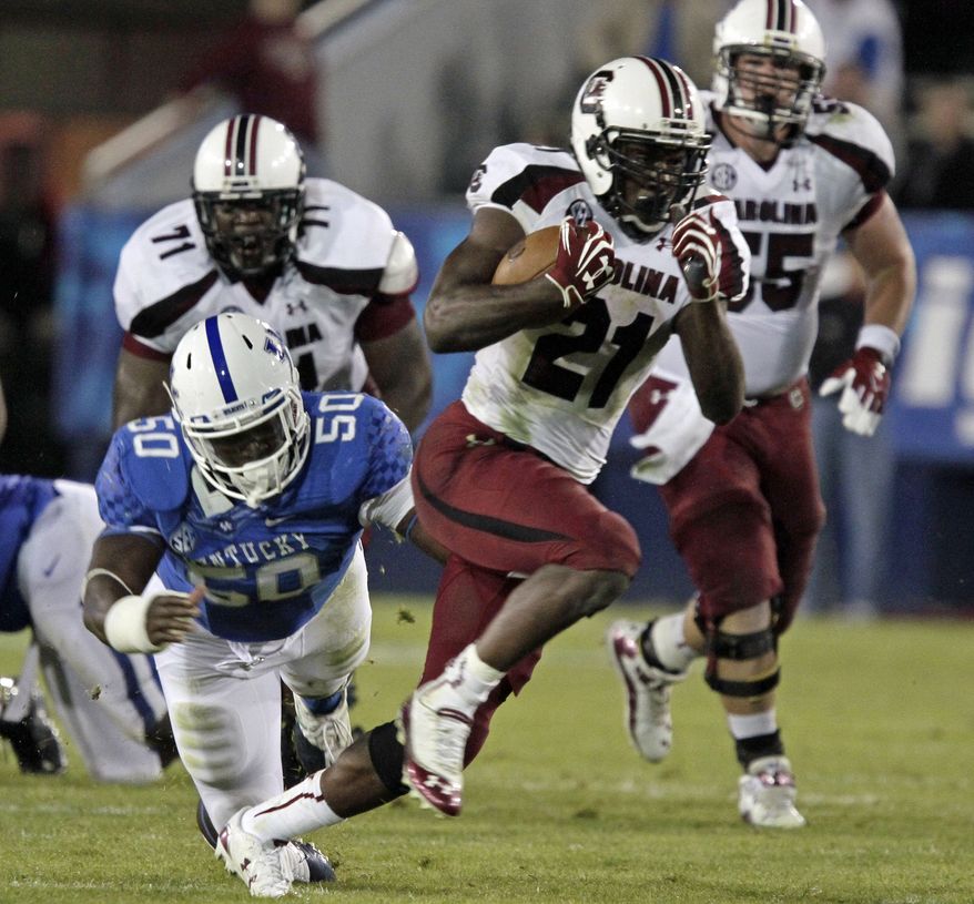 FILE - This Sept. 29, 2012, file photo shows South Carolina running back Marcus Lattimore (21) running away from Kentucky's Mike Douglas (50) during the second half of an NCAA college football game in Lexington, Ky. Lattimore will enter the NFL draft, said people familiar with the decision. One person said Monday, Dec. 10, 2012, that Lattimore is expected to announce his decision later this week. The people spoke with The Associated Press on condition of anonymity because there has not been an official statements regarding Lattimore's decision. (AP Photo/Garry Jones, File)