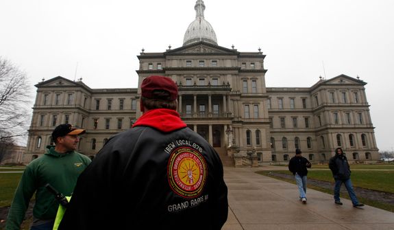 ** FILE ** International Brotherhood of Electrical Workers members stand outside the capitol in Lansing, Friday, Dec. 7, 2012. (AP Photo/Paul Sancya)