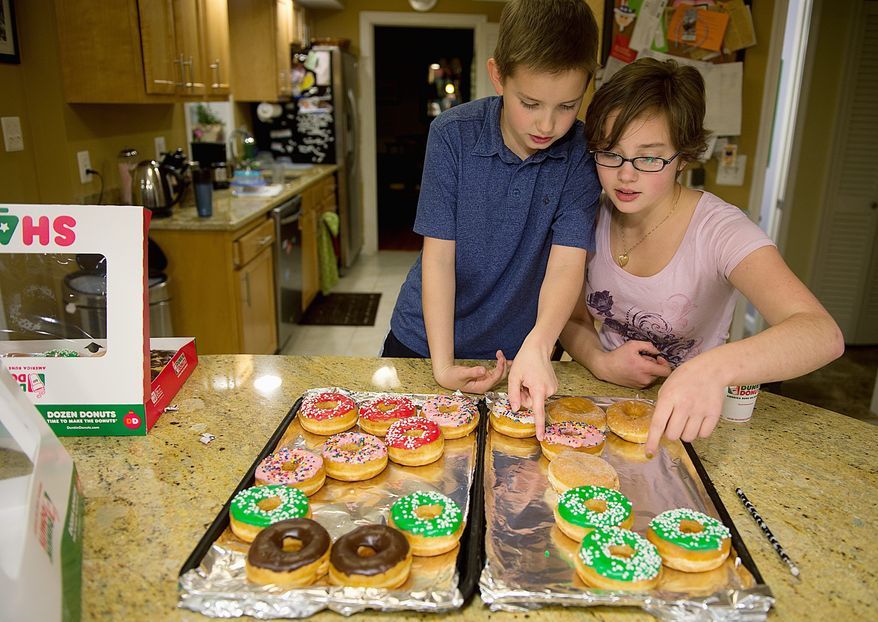Wil Hiday gets help from sister Chase, 15, to arrange doughnuts in the shape of the number “12” on two cookie sheets in their Vienna, Va., home on Tuesday. Wil turns 12 on 12/12/12 and plans to bring the dozen to school to share with friends. (Barbara L. Salisbury/The Washington Times)