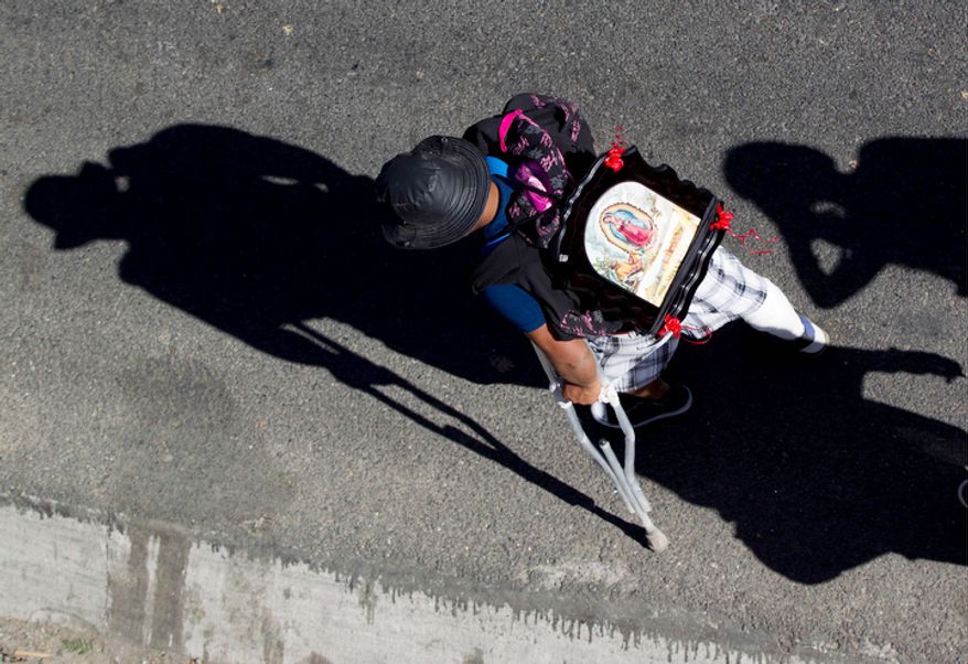 A man using crutches carries an image of the Virgin of Guadalupe on his back as he walks along a highway entering the capital during his pilgrimage to the Basilica of Guadalupe, Tuesday Dec. 11. 2012. Nationwide, devotees of the Virgin of Guadalupe make a pilgrimage to the Basilica in honor of her Dec. 12 feast day. (AP Photo/Eduardo Verdugo)