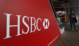 In this file photo, pedestrians pass a sign with the HSBC logo in Hong Kong on Monday, July 30, 2012.  On Jan. 18, 2018, the U.S. Department of Justice announced that HSBC Holdings has agreed to pay $101.5 million to settle claims it defrauded two of its clients. (AP Photo/Vincent Yu)