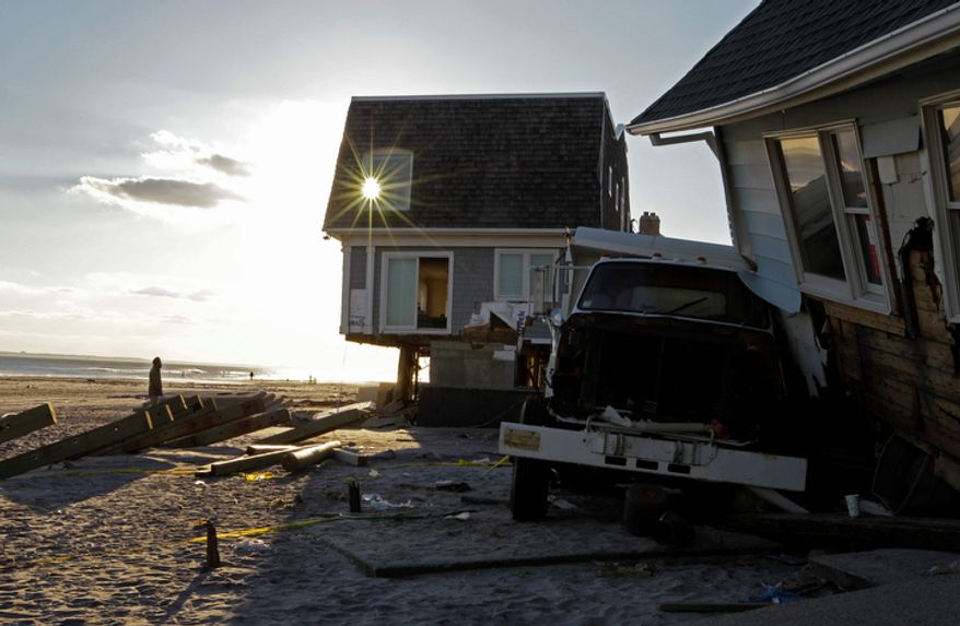 A man strolls along the sand as a burst of sunlight passes through the window of a beachfront house badly damaged in Superstorm Sandy in the Belle Harbor section of the Queens borough of New York on Wednesday, Dec. 5, 2012. (AP Photo/Kathy Willens)