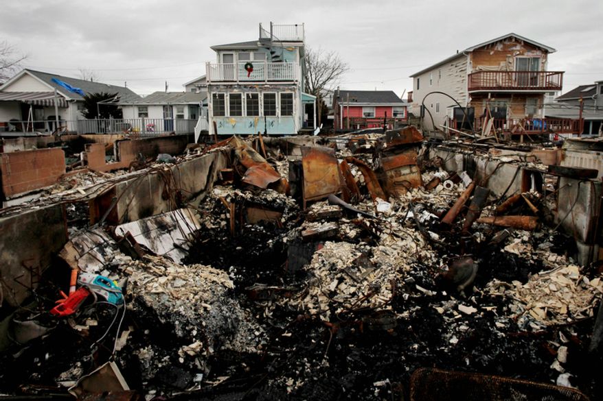 ** FILE ** A Christmas wreath is displayed on the second-floor porch railing of a home adjacent to the fire-damaged zone in the Breezy Point section of the New York borough of Queens on Friday, Dec. 7, 2012. More than 100 homes burned to the ground during Superstorm Sandy. (AP Photo/Mark Lennihan)