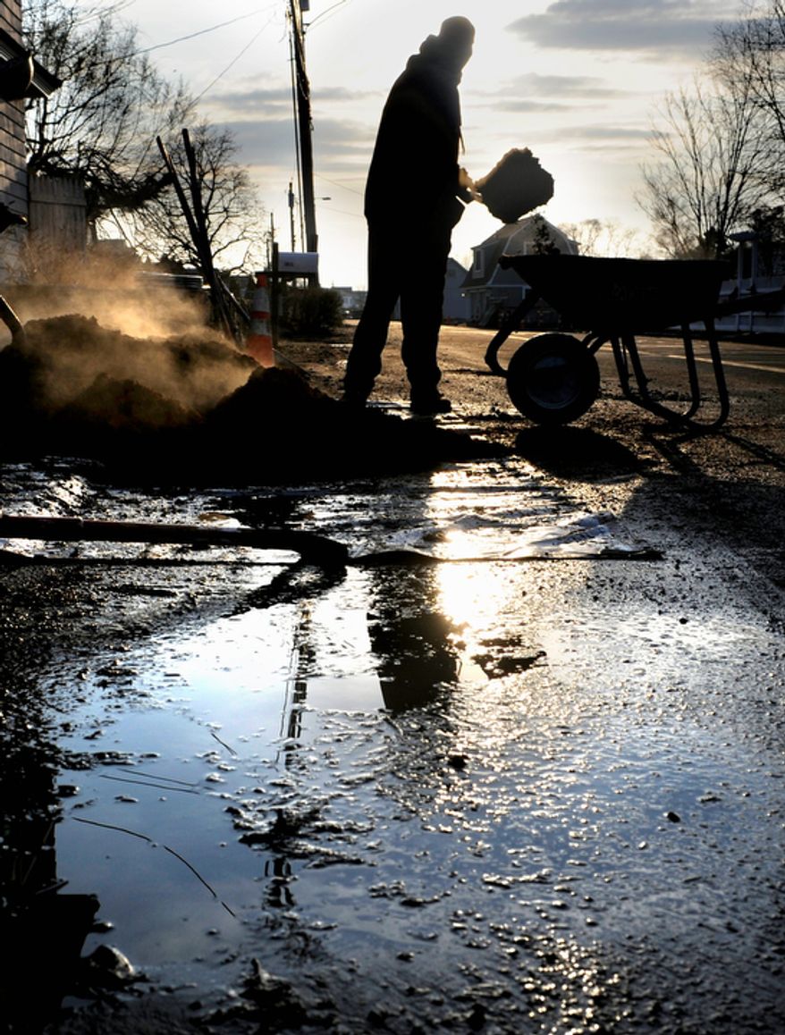 A landscaper loads mulch into a wheelbarrow at a beachfront home in Fairfield, Conn., on Tuesday, Dec. 4, 2012. The national economy is expected to absorb the blow from superstorm Sandy with little long-term damage, but in the short term, at least, Sandy is introducing dramatic booms and busts across the Northeast. (AP Photo/Jessica Hill)