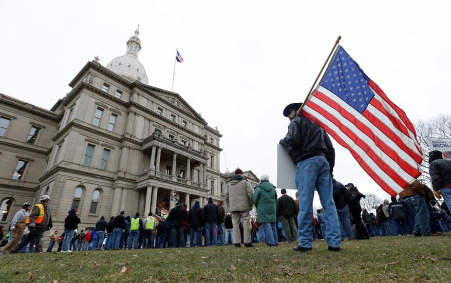 A protester holds an American flag at a rally on the State Capitol grounds in Lansing, Mich., Tuesday, Dec. 11, 2012. The crowd is protesting right-to-work legislation passed last week. (AP Photo/Paul Sancya)