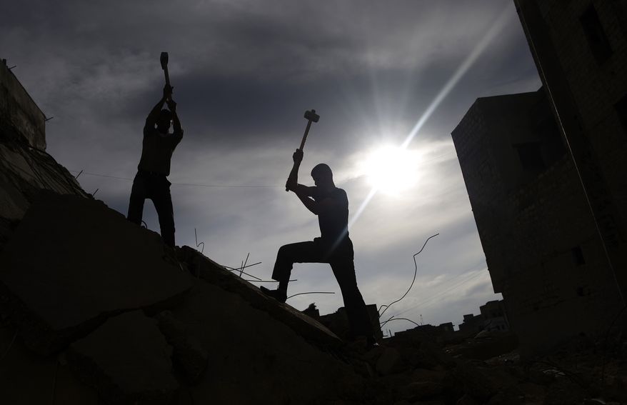 Syrian men use sledgehammers to break the concrete of a residential building in Maaret Misreen, near Idlib, Syria, on Dec. 12, 2012, while searching for belongings under the rubble. The building was destroyed in a government airstrike. (Associated Press)