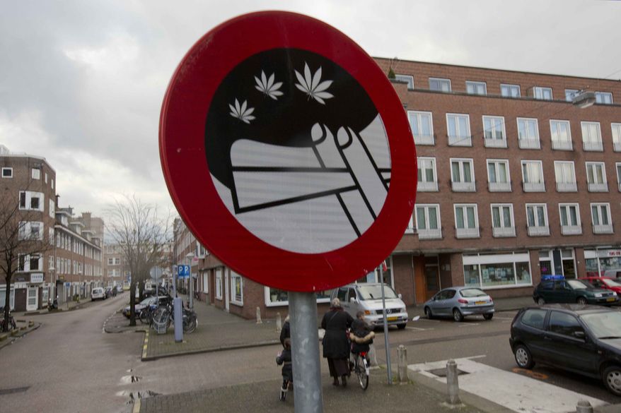 Mothers and their children leave a nearby school as a sign prohibiting the use of marijuana in a designated area is seen in Amsterdam, Wednesday, Dec. 12, 2012. (AP Photo/Peter Dejong)
