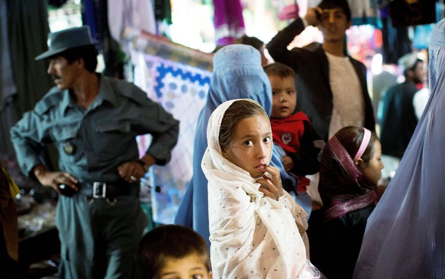 A young Afghan girl shops with her mother in October in a crowded bazaar in the capital of Helmand province, Lashkar Gah. (Associated Press)