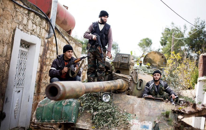 Kurdish members of the Free Syria Army ride on a tank stolen from the Syrian army in Fafeen village, north of Aleppo, in Syria on Wednesday. The rebels have made significant gains on the ground in Damascus, Deir al-Zour and Aleppo, where they have overrun military bases. (Associated Press)