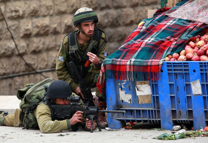 Israeli soldiers take aim during clashes with Palestinians, not seen, during the funeral of Mohammed Suleima, 17, in the West Bank city of Hebron, Thursday, Dec. 13, 2012. Thousands of Palestinians marched through the streets of this West Bank city on Thursday, chanting anti-Israel slogans and waving green Hamas flags during a funeral procession for a teenager killed by Israeli troops. (AP Photo/Nasser Shiyoukhi)