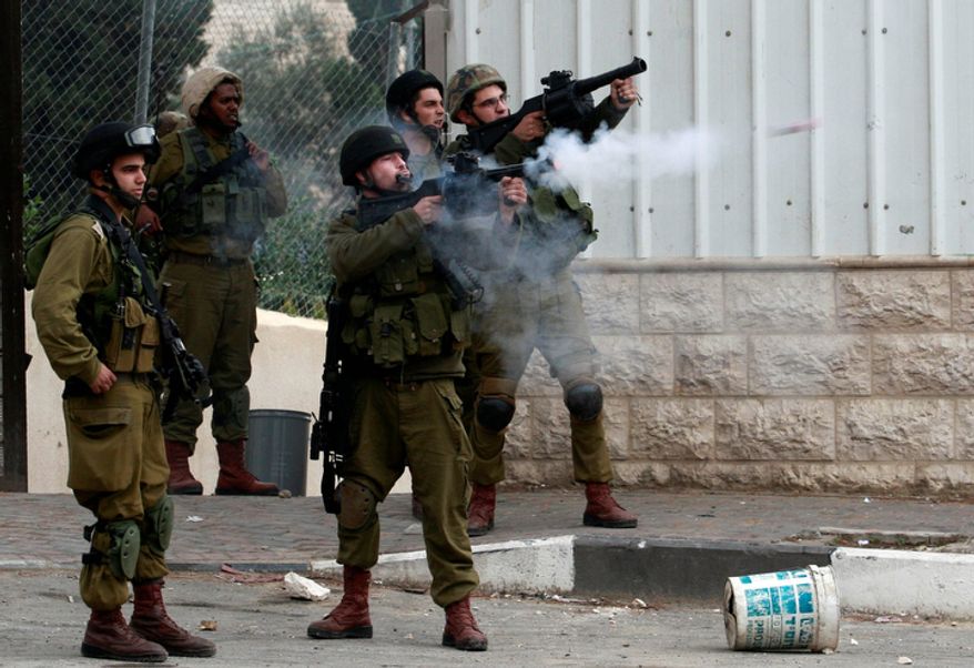 An Israeli soldier shoots a tear gas canister towards Palestinians, not seen, during the funeral Mohammed Suleima, 17, in the West Bank city of Hebron, Thursday, Dec. 13, 2012. (AP Photo/Nasser Shiyoukhi)