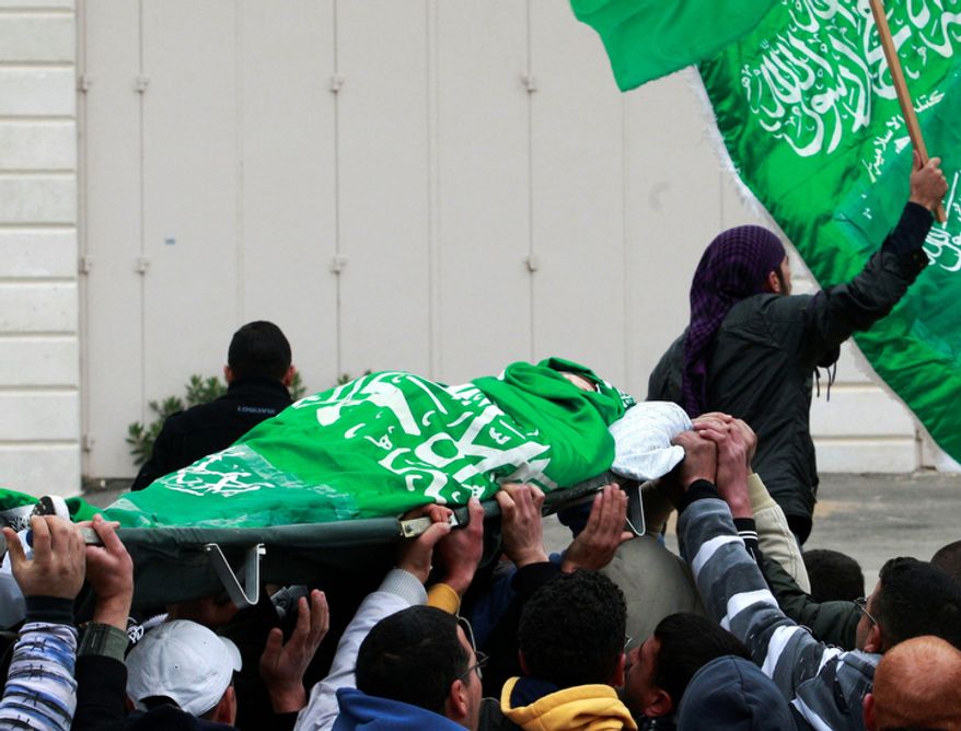 Palestinians carry the body of Mohammed Suleima, 17, during his funeral in the West Bank city of Hebron, Thursday, Dec. 13, 2012. Thousands of Palestinians marched through the streets of this West Bank city on Thursday, chanting anti-Israel slogans and waving green Hamas flags during a funeral procession for a teenager killed by Israeli troops. (AP Photo/Nasser Shiyoukhi)