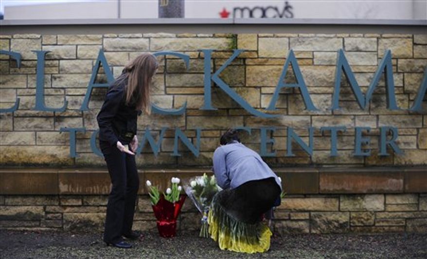 Leslie King, right and Tenille Beseda place flowers Wednesday, Dec. 12, 2012, at the entrance to the scene of a multiple shooting yesterday at Clackamas Town Center Mall in Portland, Ore. A gunman who opened fire on shoppers at the mall had no connection to the two people he fatally shot and wanted to kill as many people as possible, police said Wednesday. (AP Photo/Greg Wahl-Stephens)