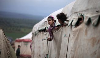 Syrian girls who fled their homes with their families peek out of their makeshift school at a camp for displaced Syrians in the village of Atmeh, Syria, on Dec. 10, 2012. (Associated Press)