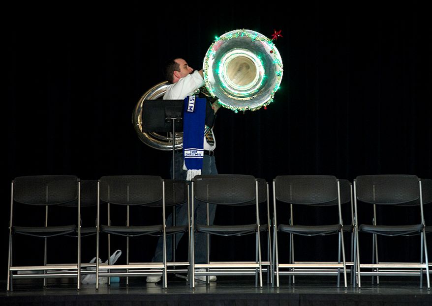 Tom Newman of Ashburn, Va. turns on the Christmas lights on his tuba before the start of the rehearsal for Tuba Christmas at the Millennium Stage at the Kennedy Center. (Barbara L. Salisbury/The Washington Times)
