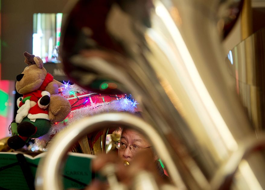 A tuba player is seen through another tuba while he rehearses with hundreds of other tubists at the Millennium Stage at the Kennedy Center in Washington, D.C. on Thursday, Dec. 13, 2012 for Tuba Christmas, an annual concert of tuba players. This is the 39th year for the concert, which started in Rockefeller Center in 1974. It is now held worldwide. (Barbara L. Salisbury/The Washington Times)