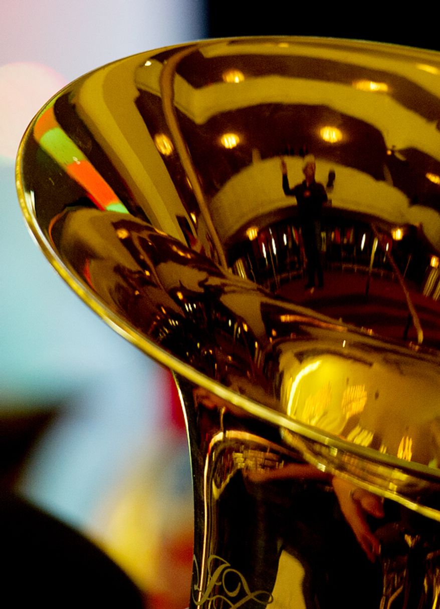 One of the conductors for Tuba Christmas 2012 is seen reflected in a tuba during rehearsal at the Kennedy Center's Millennium Stage. (Barbara L. Salisbury/The Washington Times)
