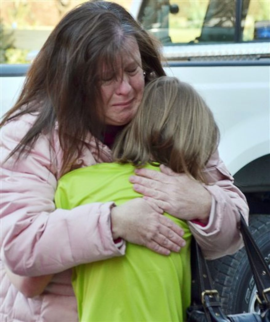 A mother hugs her daughter following the shootings at the Sandy Hook Elementary School in Newtown, Conn., about 60 miles northeast of New York City, on Friday, Dec. 14, 2012. (AP Photo/The New Haven Register, Melanie Stengel)