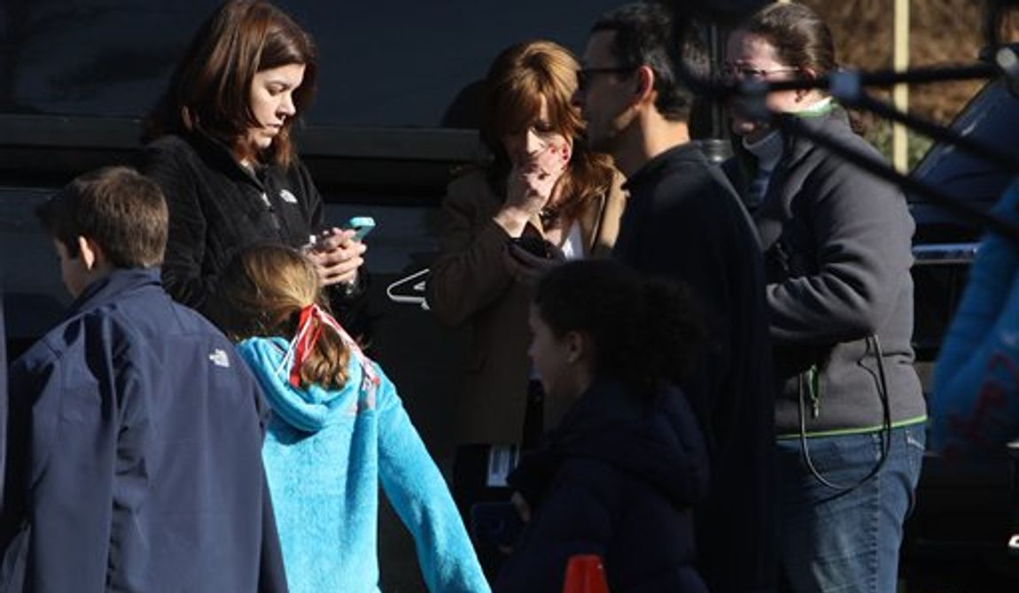 A woman weeps as she arrives to pick up her children at the Sandy Hook Elementary School, Friday, Dec. 14, 2012 in Newtown, Conn. A man opened fire inside the Connecticut elementary school where his mother worked Friday, killing 26 people, including 18 children, and forcing students to cower in classrooms and then flee with the help of teachers and police. (AP Photo/The Journal News, Frank Becerra Jr.) MANDATORY CREDIT, NYC OUT, NO SALES, TV OUT, NEWSDAY OUT; MAGS OUT